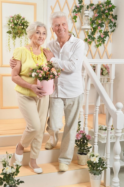 Feliz pareja senior en casa con flores.