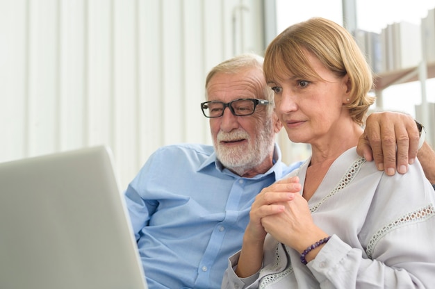 Feliz pareja senior caucásica usando laptop en casa