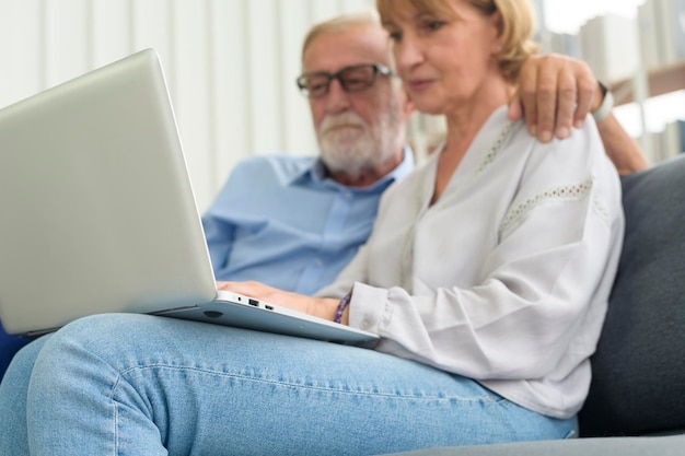 Feliz pareja senior caucásica usando laptop en casa