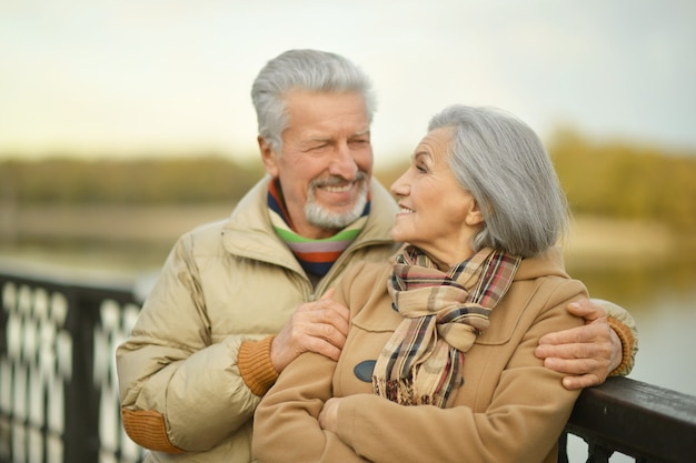 Feliz pareja senior cerca del río en otoño