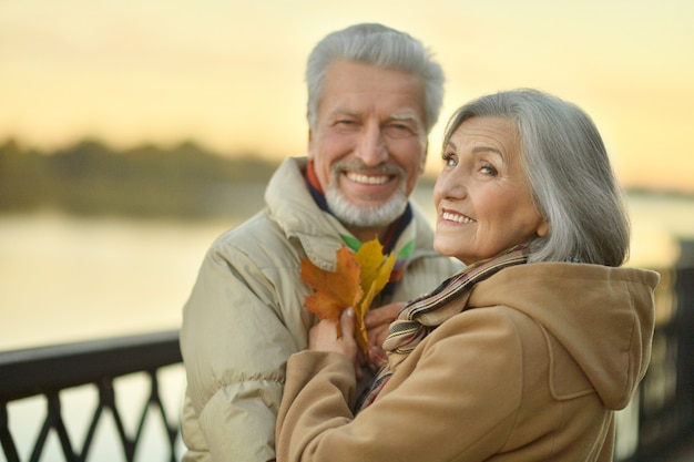 Feliz pareja senior cerca del río en otoño