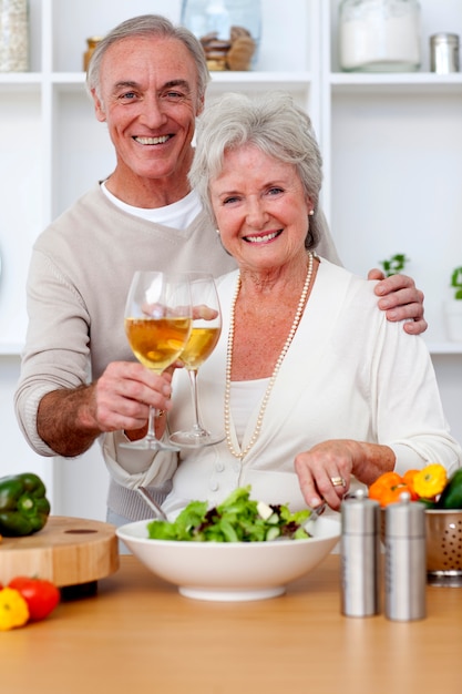 Feliz pareja senior comiendo una ensalada en la cocina