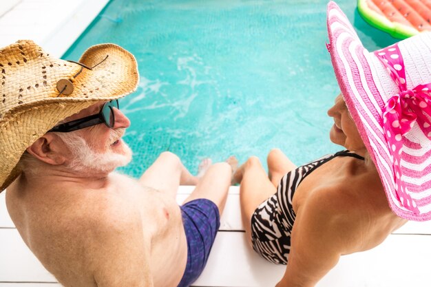 Feliz pareja senior de fiesta en la piscina