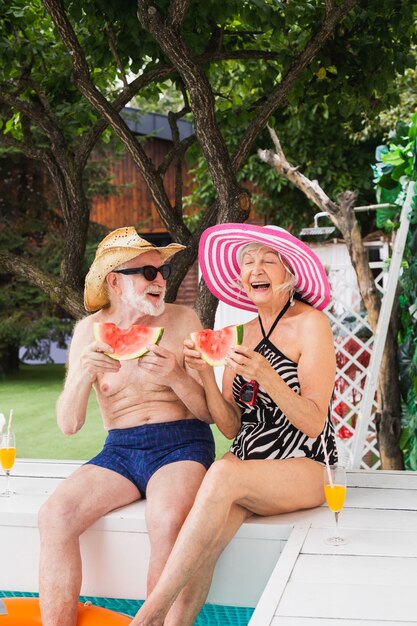 Feliz pareja senior de fiesta en la piscina