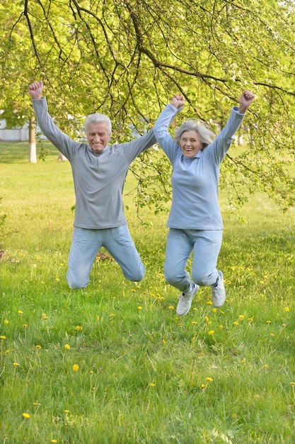 Feliz pareja senior en forma saltando en el parque
