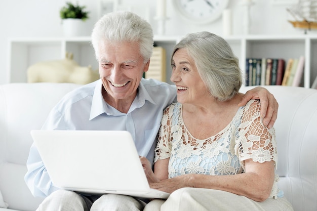 Feliz pareja senior con laptop en casa