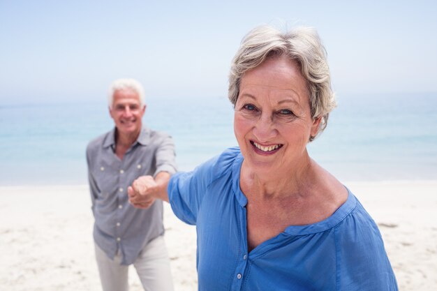 Feliz pareja senior mano en la playa