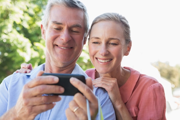 Feliz pareja senior mirando smartphone