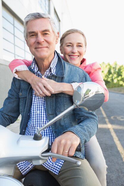 Feliz pareja senior montando un ciclomotor