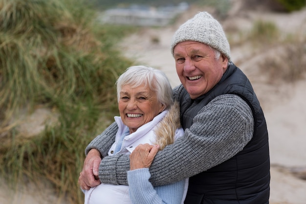 Feliz pareja senior de pie juntos en la playa