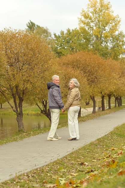 Foto feliz pareja senior a pie en el parque otoño