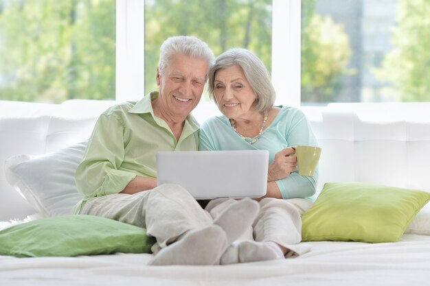 Feliz pareja senior con portátil en casa