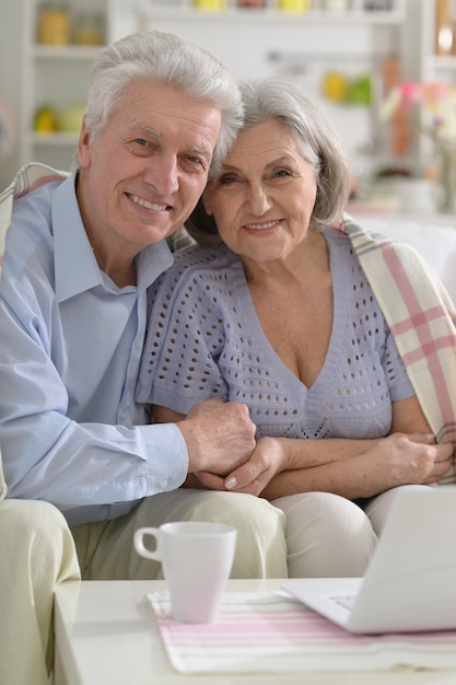 Feliz pareja senior con portátil en casa