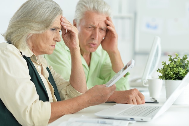 Feliz pareja senior con portátil en la oficina