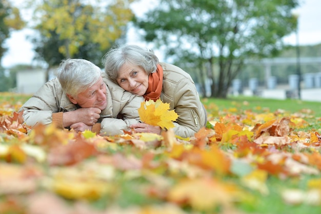 Feliz pareja senior posando en el parque de otoño