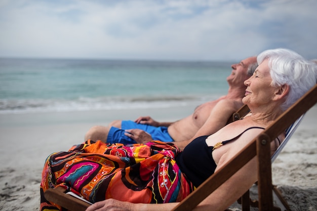 Feliz pareja senior relajante en tumbonas en la playa