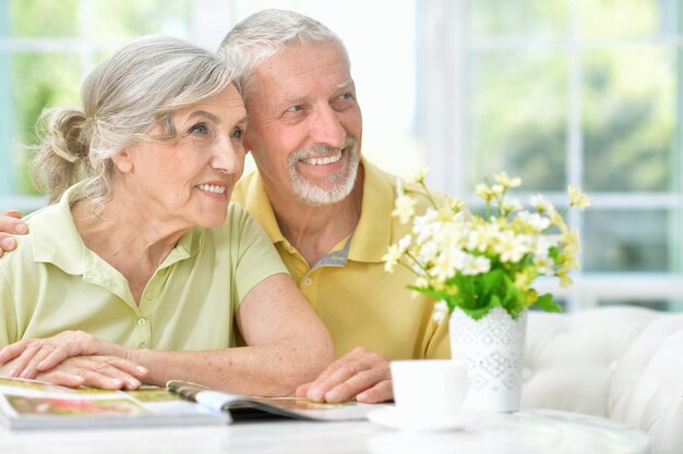 Feliz pareja senior con revista bebiendo té en la cocina