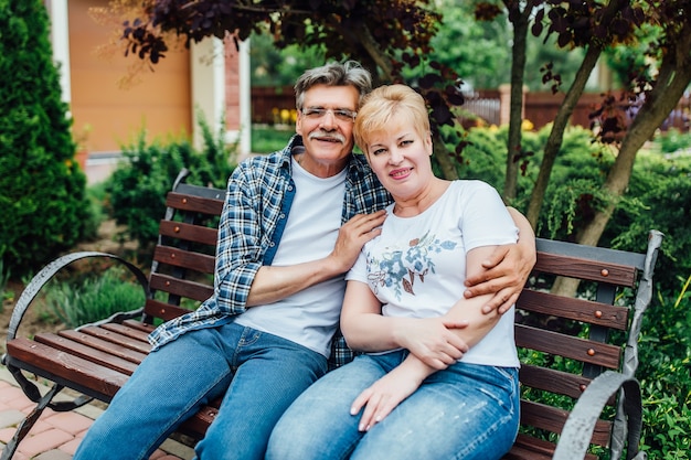 Feliz pareja senior sentada cerca de casa ahd posando para la foto.