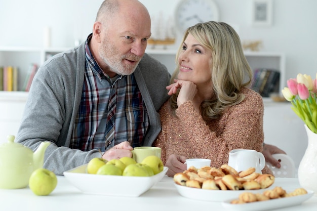 Feliz pareja senior sentada en la mesa de la cocina