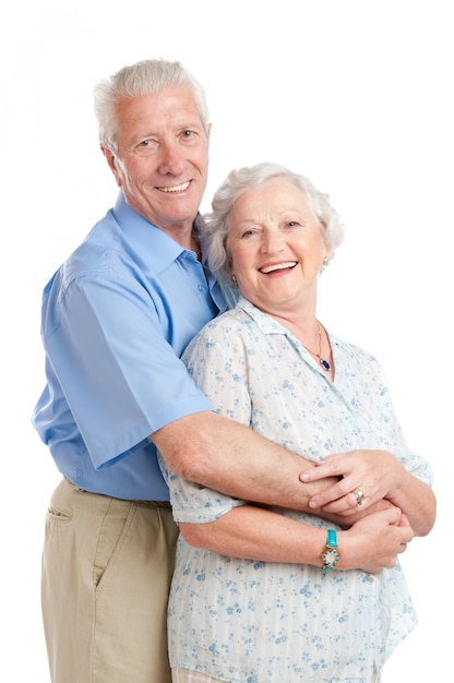 Feliz pareja senior sonriente de pie junto con un abrazo aislado en blanco