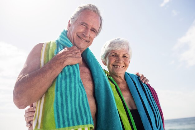 Feliz pareja senior sosteniendo una toalla alrededor del cuello