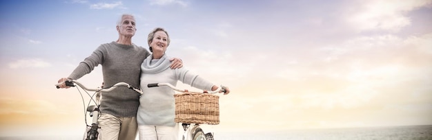 Feliz pareja senior con su bicicleta en la playa