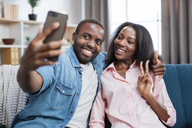 Feliz pareja sentada en abrazos y tomando selfie en el móvil