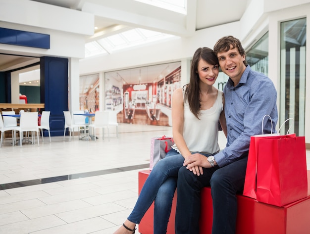 Feliz pareja sentada en el centro comercial