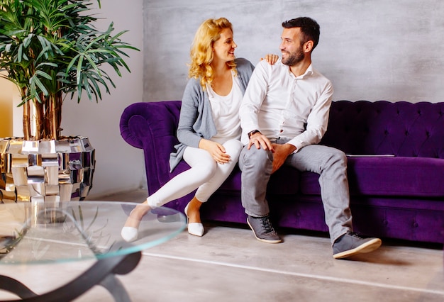 Feliz pareja sentada en un cómodo sofá en la sala de estar