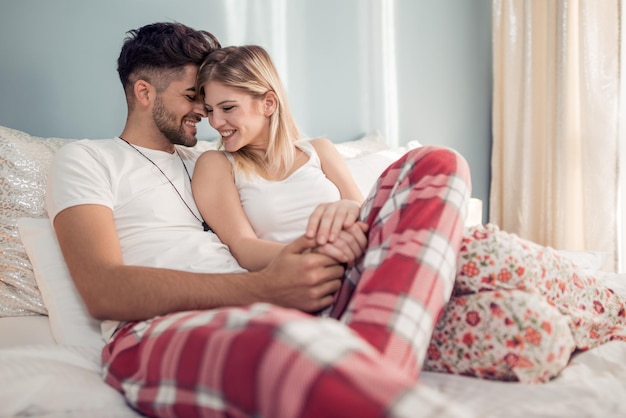 Feliz pareja sentada en el dormitorio