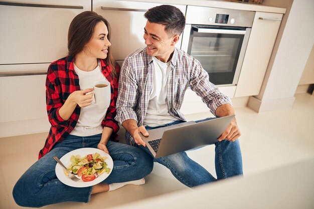 Feliz pareja sentada en el piso de la cocina