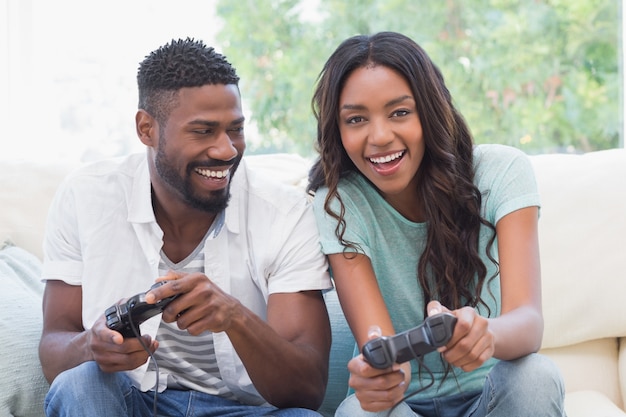 Feliz pareja en el sofá jugando videojuegos