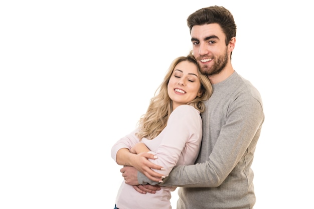 La feliz pareja sonríe sobre el fondo blanco.