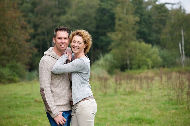 Feliz pareja sonriendo y abrazando al aire libre