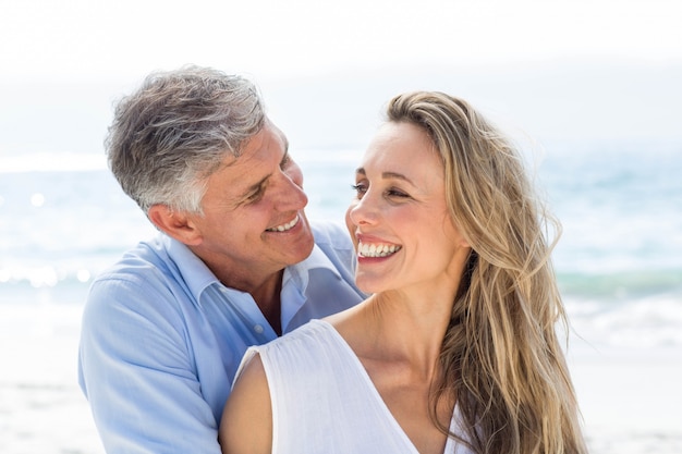 Feliz pareja sonriendo el uno al otro junto al mar