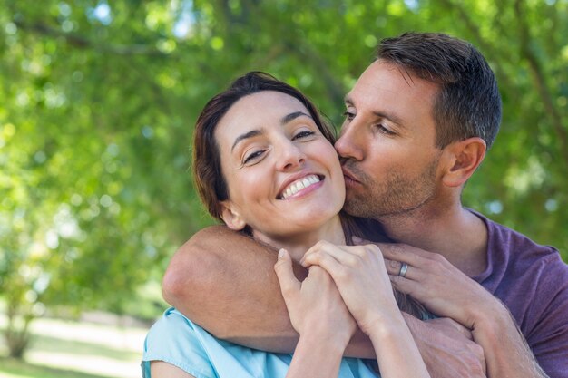 Feliz pareja sonriendo a la cámara en el parque