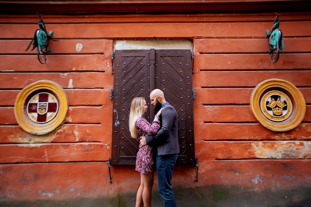 Feliz pareja sonriendo, de pie cerca de la pared en los brazos