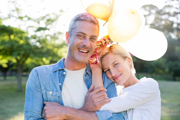 Feliz pareja sosteniendo globos en el parque