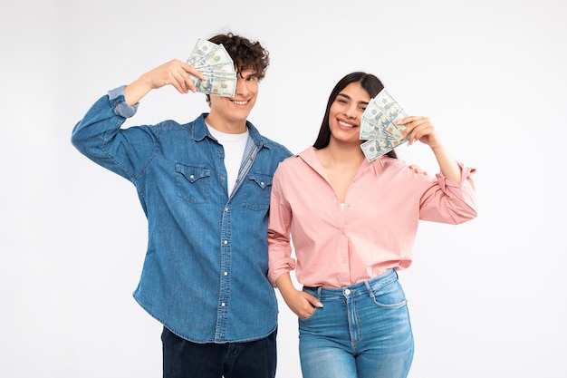 Feliz pareja sosteniendo un montón de billetes de dinero sobre fondo blanco.