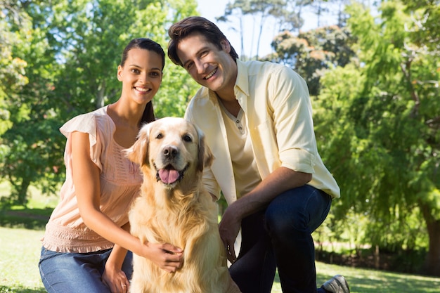 Feliz pareja con su perro en el parque en un día soleado