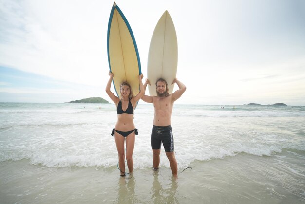Foto feliz pareja surfeando juntos en la playa con tabla de surf en pattaya tailandia