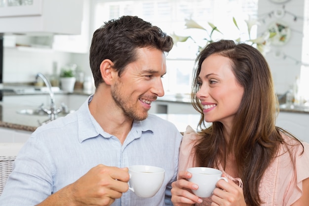 Feliz pareja con tazas de café en la cocina