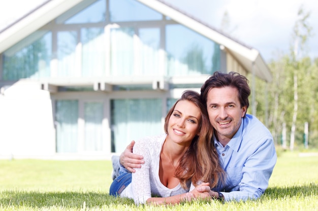 Feliz pareja tendida frente a su casa