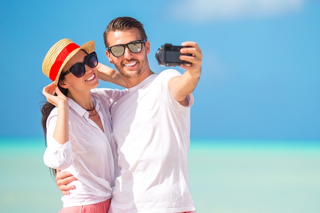 Foto feliz pareja tomando una foto en la playa blanca en vacaciones de luna de miel