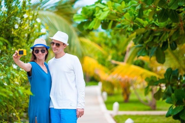 Feliz pareja tomando una foto en la playa blanca en vacaciones de luna de miel