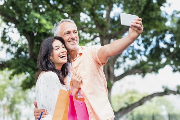 Feliz pareja tomando selfie con bolsas de compras