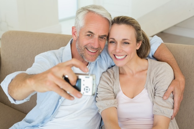 Feliz pareja tomando un selfie juntos en el sofá