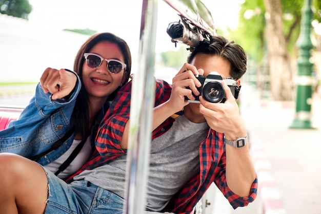 Feliz pareja de turistas asiáticos viajando en taxi Tuk Tuk en Bangkok Tailandia