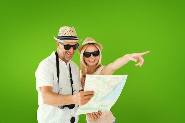 Feliz pareja de turistas usando un mapa y apuntando contra una viñeta verde