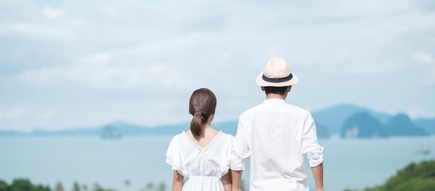 Feliz pareja viajera con camisa blanca y vestido disfruta de hermosas vistas Los turistas de pie y relajándose sobre el océano viajan juntos aman el concepto de verano y vacaciones